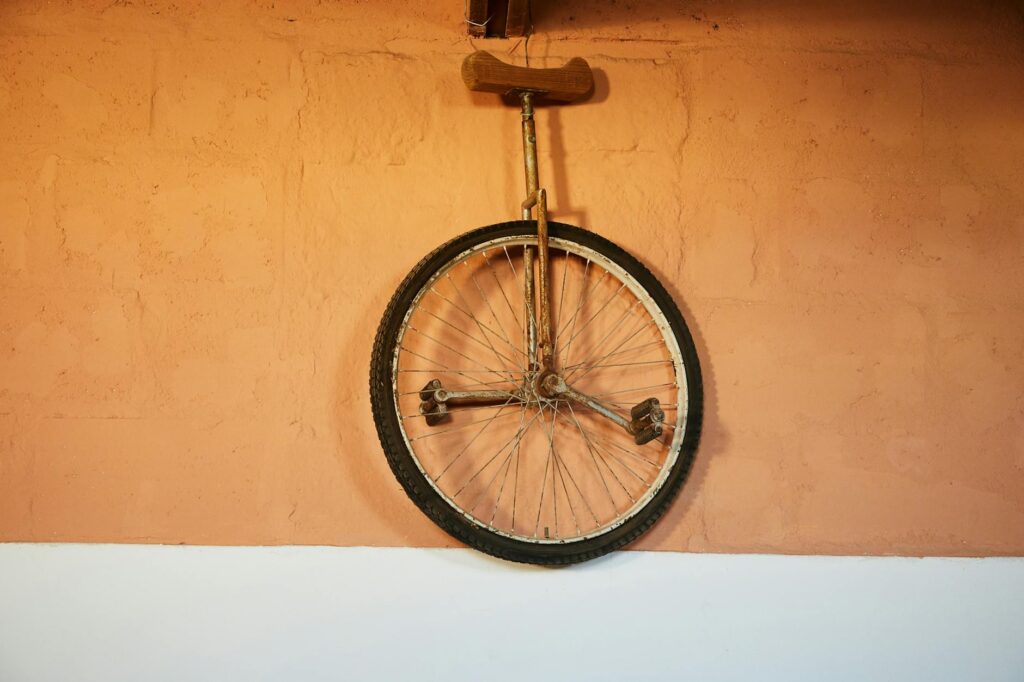 old shabby unicycle hanging on brick wall
